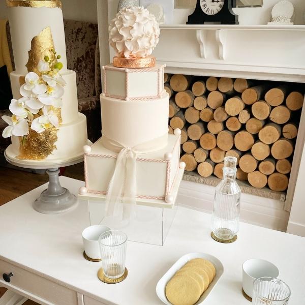 Wedding cake consultation table, a while and gold leaf wedding cake, a geometric wedding cake with glasses and biscuits